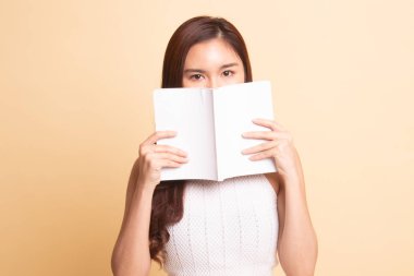 Bej renkli arka plan üzerinde bir kitapla genç Asyalı kadın