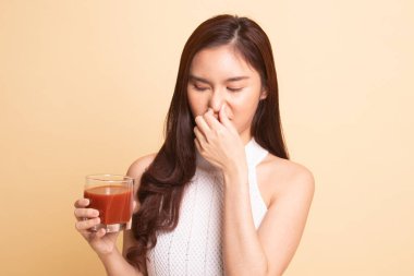 Genç Asyalı kadın bej arka planda domates suyundan nefret eder.