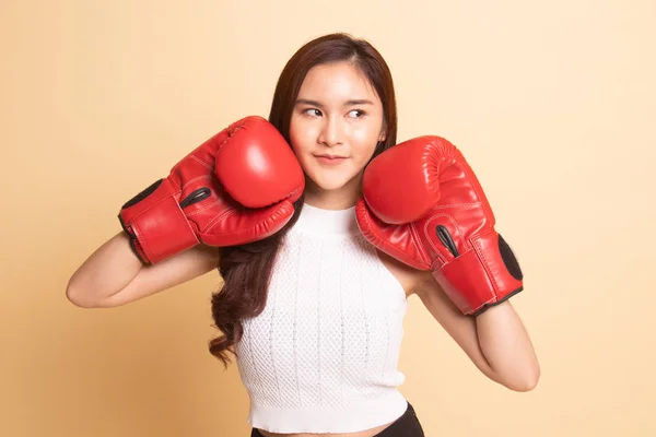 Young Asian woman with red boxing gloves   on beige background