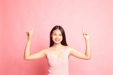 Genç Asyalı kadın pembe arka plandaki boşluğu işaret ediyor