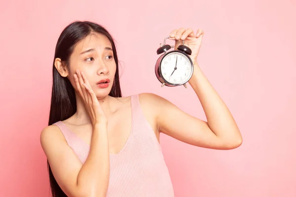 年轻的亚裔妇女被强调以一个时钟在粉红色背景 — 图库照片