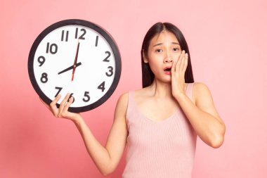 Sabah bir saat ile uykulu genç Asyalı kadın.