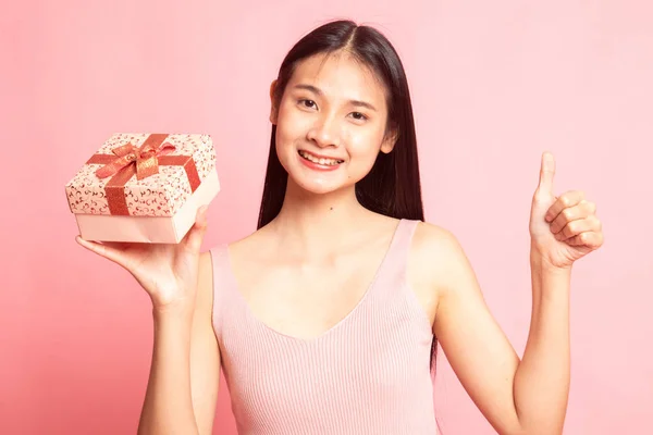 Азиатка поднимает большой палец с подарочной коробкой . — стоковое фото