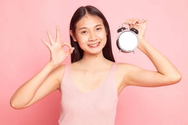 Jeune asiatique femme montrer OK avec une horloge . — Photo