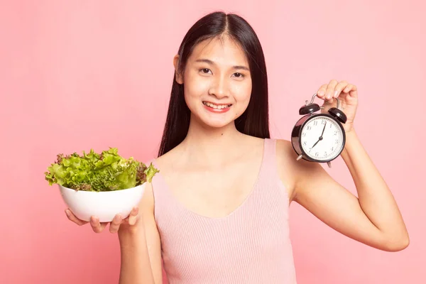 Ung asiatisk kvinna med klocka och sallad. — Stockfoto