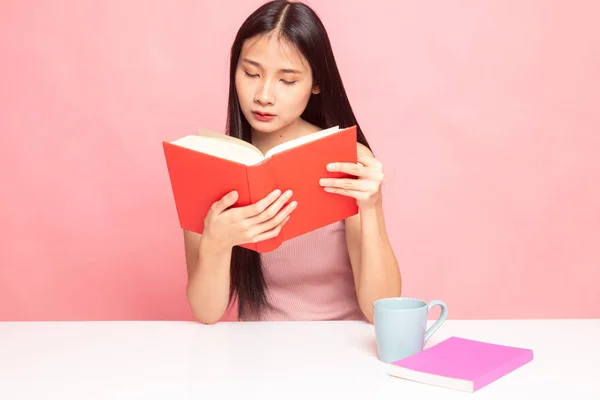 Junge asiatische Frau liest ein Buch mit einer Tasse Kaffee. — Stockfoto