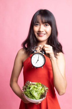 Saat ve salata ile genç Asyalı kadın.