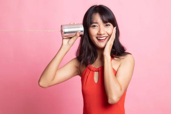 Счастливая молодая азиатка слушает жестяную банку телефона . — стоковое фото