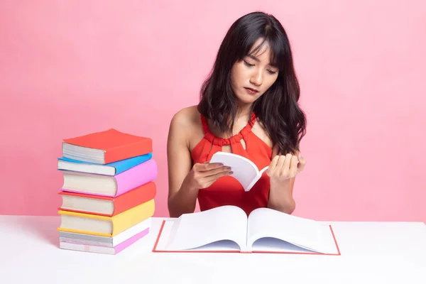 Ung asiatisk kvinna läsa en bok med böcker på bord. — Stockfoto