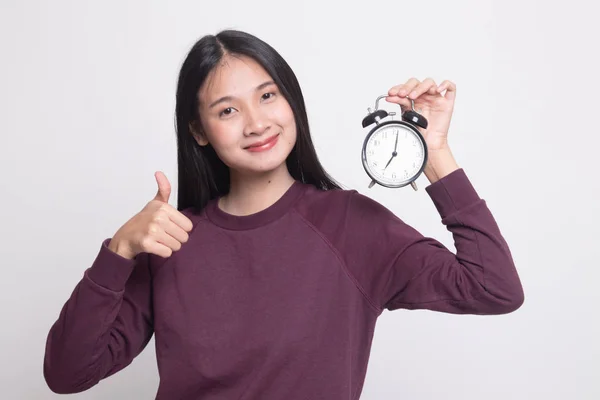 Jeune asiatique femme montrer pouces vers le haut avec une horloge . — Photo