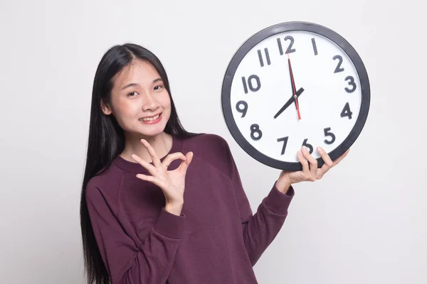 Jeune asiatique femme montrer OK avec une horloge . — Photo