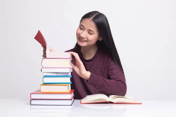 Junge Asiatin liest ein Buch mit Büchern auf dem Tisch. — Stockfoto