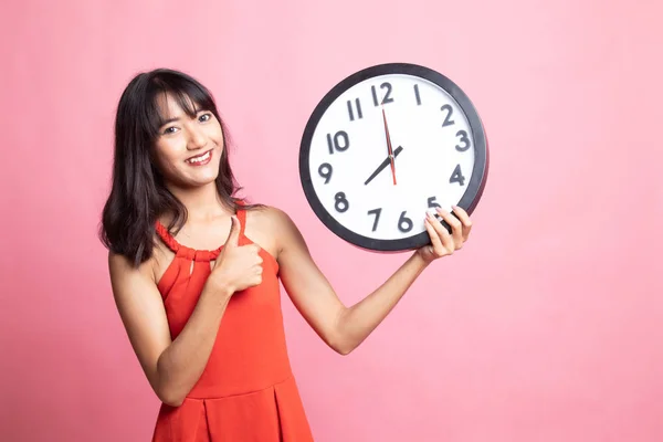 Young Asian woman thumbs up with a clock. — Stock Photo, Image