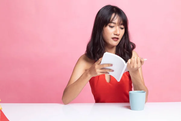 Junge asiatische Frau liest ein Buch mit einer Tasse Kaffee. — Stockfoto