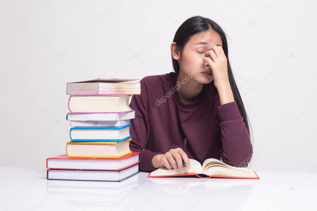 Exhausted Asian woman got headache read a book with books on tab