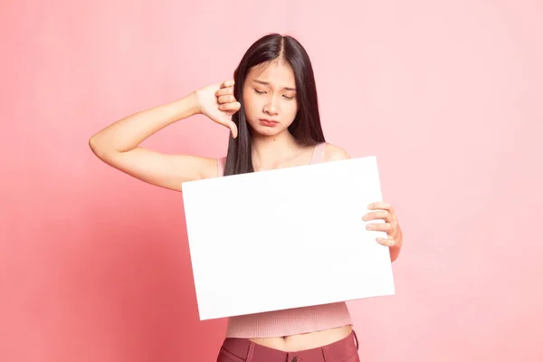 Ung asiatisk kvinna visar tummen ner med vit blank skylt. — Stockfoto