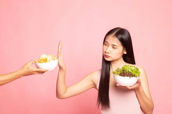 Jonge Aziatische vrouw met salade nee zeggen tegen potato chips. — Stockfoto