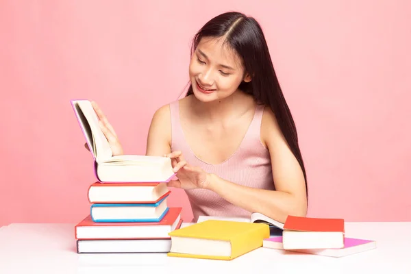 Junge Asiatin liest ein Buch mit Büchern auf dem Tisch. — Stockfoto