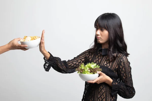 Молодая азиатка с салатом говорит нет картофельным чипсам . — стоковое фото