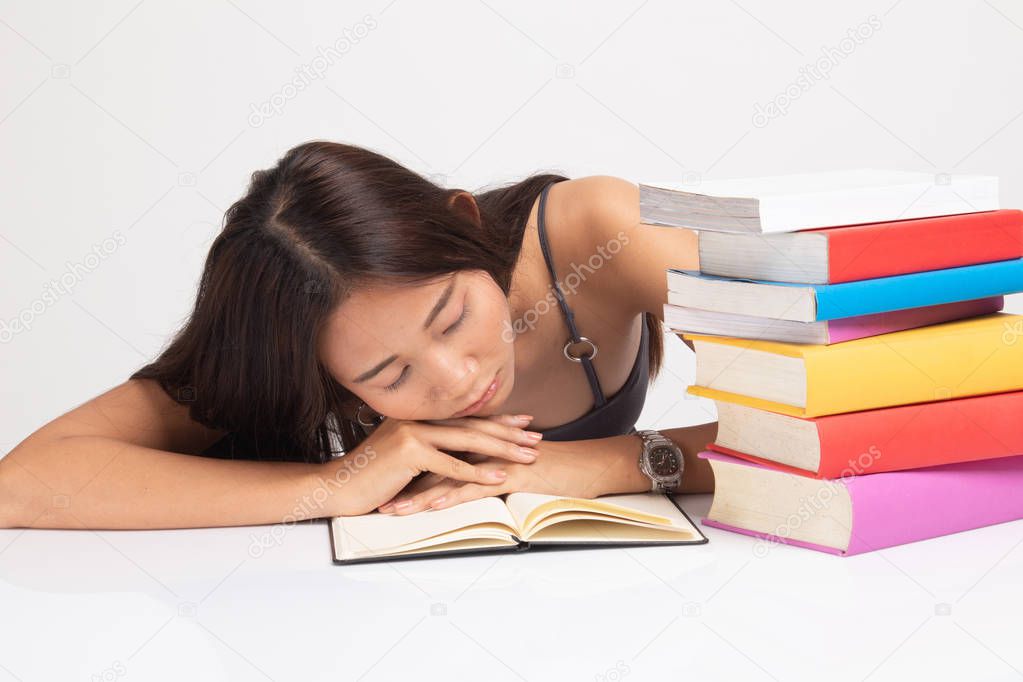 Exhausted Young Asian woman sleep with books on table.