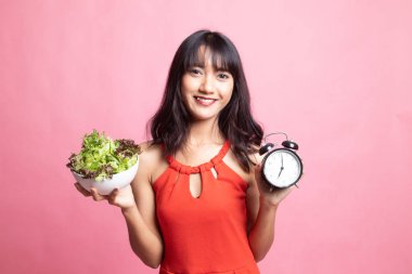 Saat ve salata ile genç Asyalı kadın.