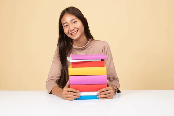 Felice giovane donna asiatica leggere un libro con libri sul tavolo . — Foto Stock