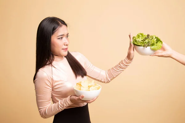ポテトチップスを持つ若いアジア女性はサラダにノーと言う. — ストック写真