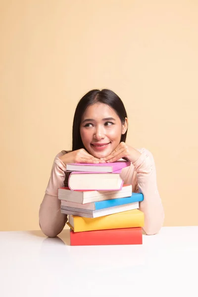 Šťastné mladé asijské ženy četl knihu s knihami na stole. — Stock fotografie