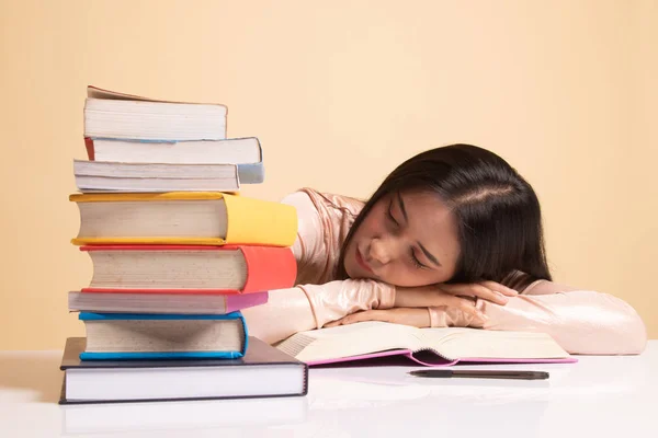 Uitgeput jonge Aziatische vrouw slapen met boeken op tafel. — Stockfoto