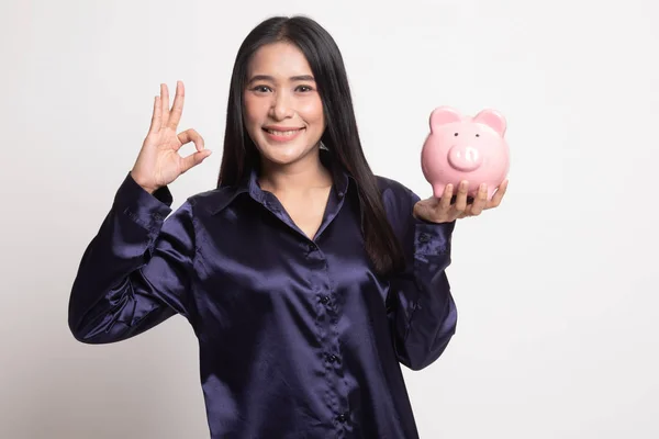 アジアの女性が豚ヘッドコイン バンクで [ok] を表示します。. — ストック写真