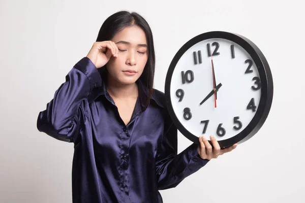 Sleepy jonge Aziatische vrouw met een klok in de ochtend. — Stockfoto