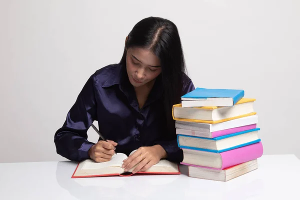 Joven mujer asiática leer un libro con libros en la mesa . — Foto de Stock