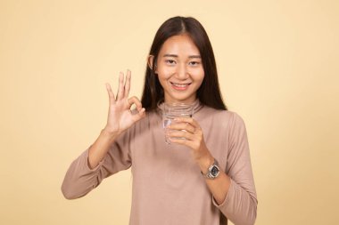 Genç Asyalı kadın göster Ok ile içme suyu bir bardak.