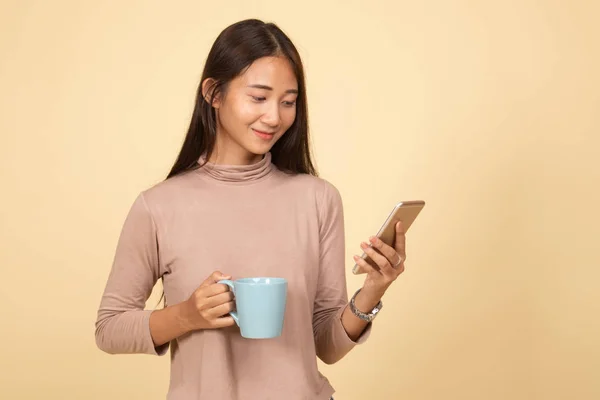Jeune femme asiatique avec téléphone mobile et tasse de café . — Photo