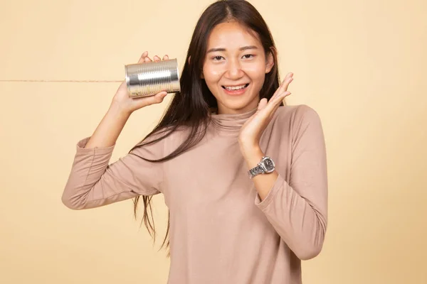 Happy Young Asian woman listen with tin can phone.