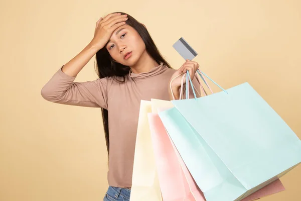 Ongelukkige jonge Aziatische vrouw met shopping tassen en credit card. — Stockfoto