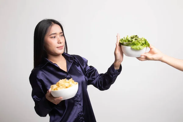 Jonge Aziatische vrouw met aardappel chips nee zeggen tegen salade. — Stockfoto