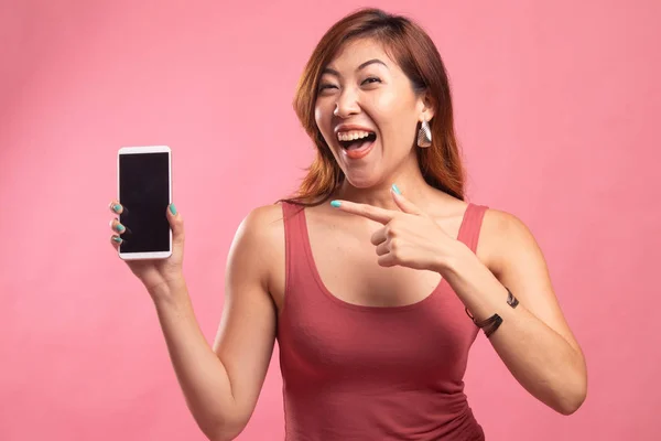Возбужденная молодая азиатка указывает на мобильный телефон . — стоковое фото