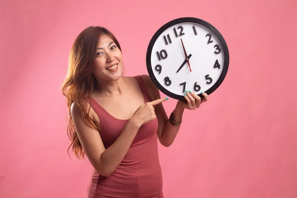 Young Asian woman point to a clock.