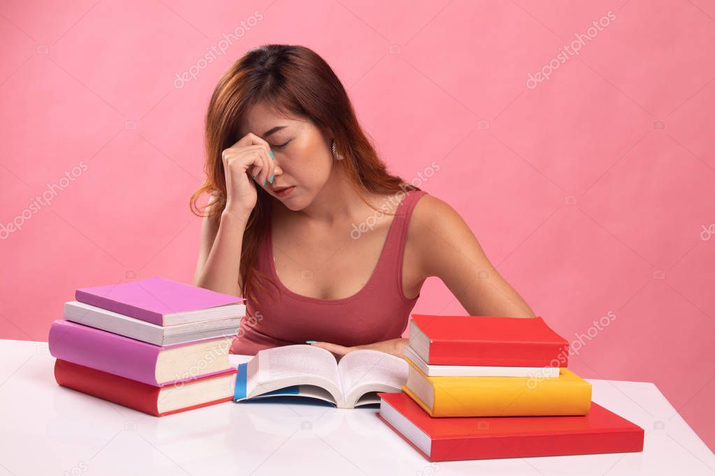 Exhausted Asian woman got headache read a book with books on tab