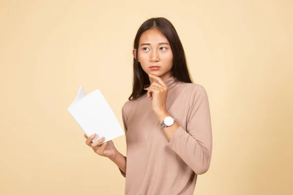 Giovane donna asiatica con un libro sta pensando . — Foto Stock