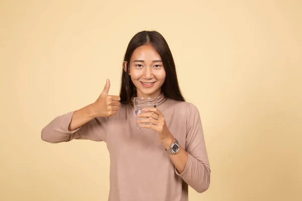 Mladá asijská žena palce se sklenicí pitné vody. — Stock fotografie