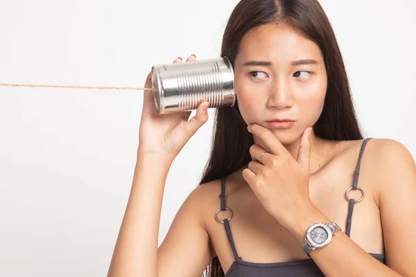 Mladá asijská žena slyšení s telefonem plechovky a myšlení. — Stock fotografie