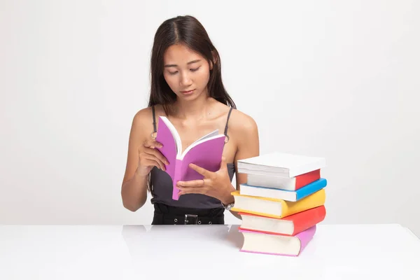 年轻的亚洲妇女读了一本桌子上有书的书. — 图库照片