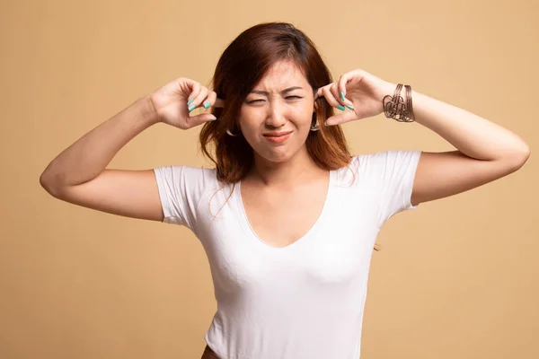 Junge asiatische Frau blockiert beide Ohren mit Fingern. — Stockfoto