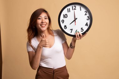 Genç Asyalı kadın başparmak yukarıya ile bir masa saati.