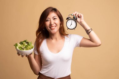Saat ve salata ile genç Asyalı kadın.