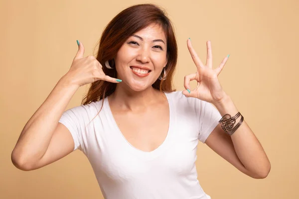 Joven asiático mujer espectáculo con el gesto del teléfono y OK signo . —  Fotos de Stock