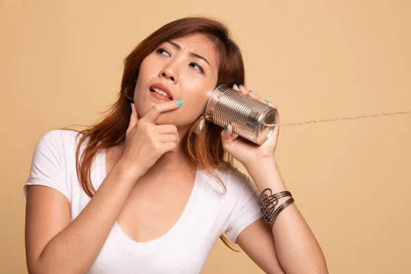 Mladá asijská žena slyšení s telefonem plechovky a myšlení. — Stock fotografie