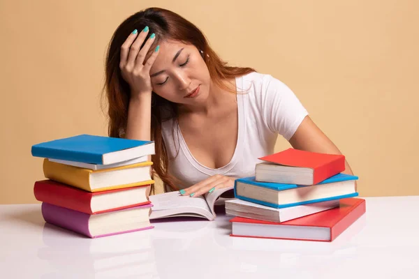 Mujer asiática joven agotada leer un libro con libros en la mesa . — Foto de Stock